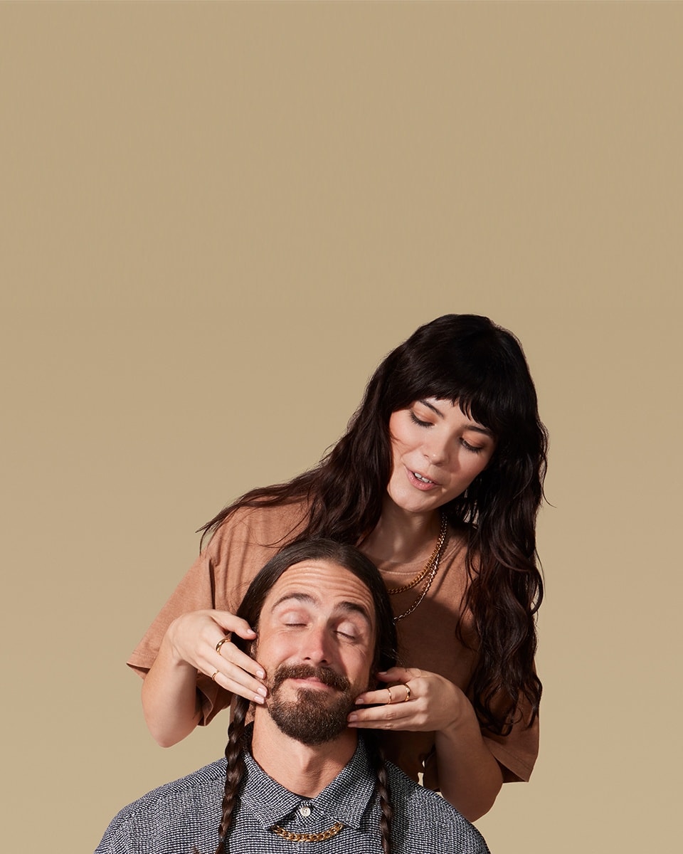 Male model sitting down having his beard massaged by female model