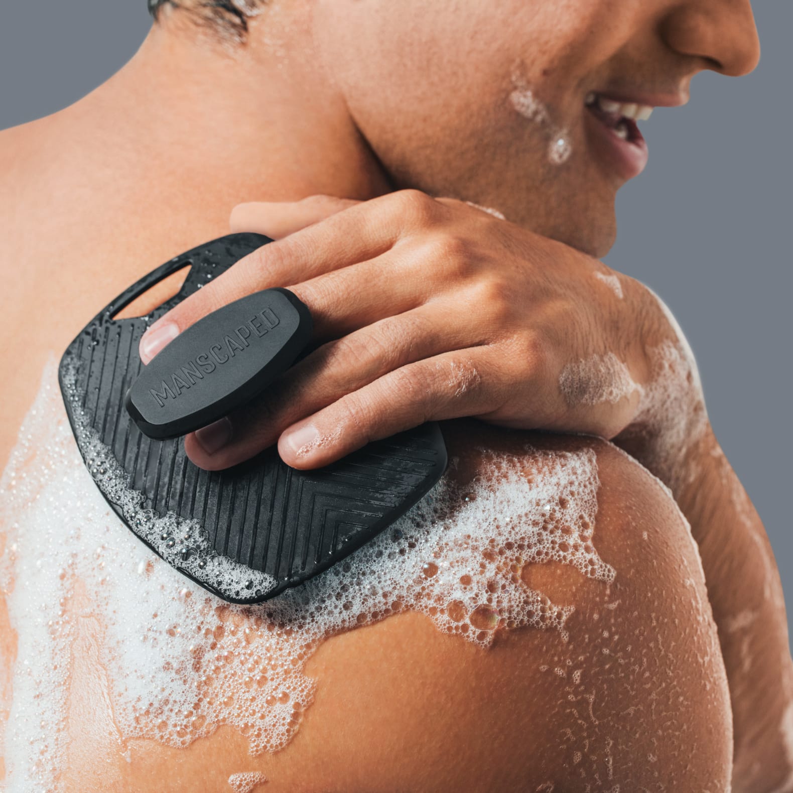 Male model using the Body Buffer on his back and holding the ergonomic handle on the back